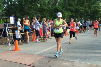 A female marathon participant crosses the finish line and checks her time.